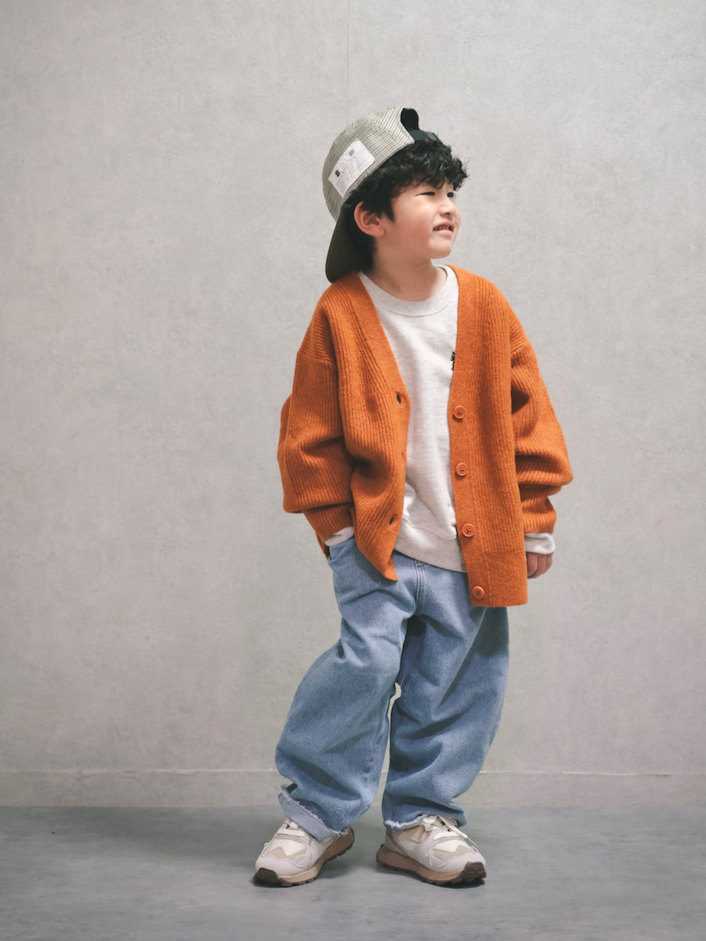 オレンジ系のニット/セーター、ホワイト系のスウェット、ブルー系のデニムパンツを着用したキッズの秋コーディネートの3枚目の写真