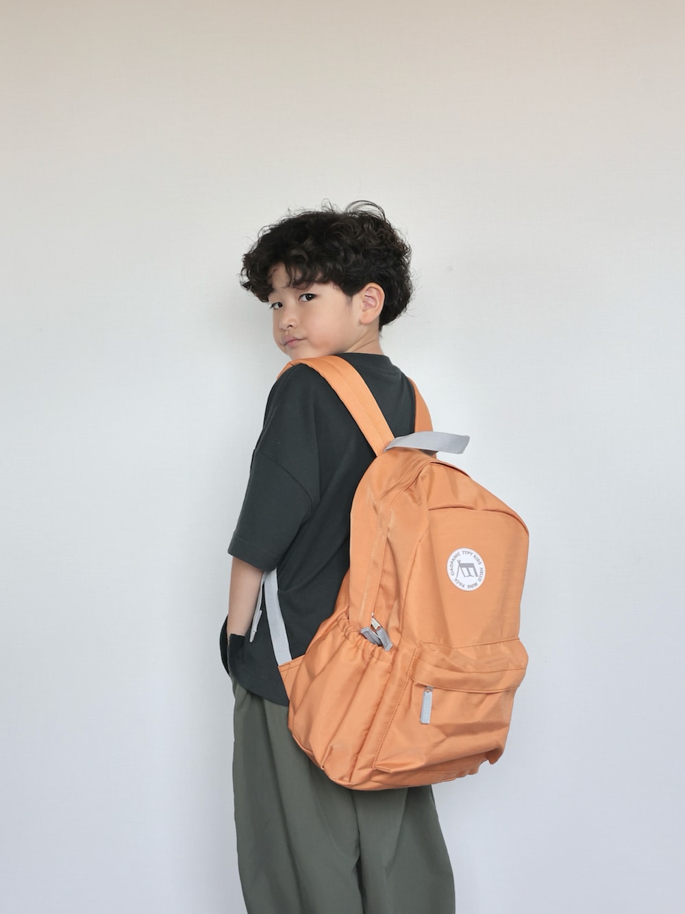 ブラック系のTシャツ/カットソー、グリーン系のその他パンツ、オレンジ系のバックパック/リュックを着用したキッズの夏コーディネートの5枚目の写真