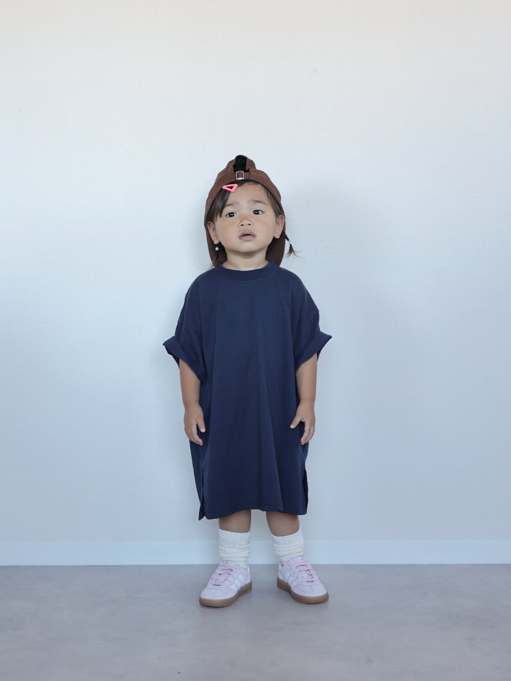 ブルー系のワンピース、ピンク系のスニーカー、ブラウン系のキャップを着用したキッズの夏コーディネートの4枚目の写真