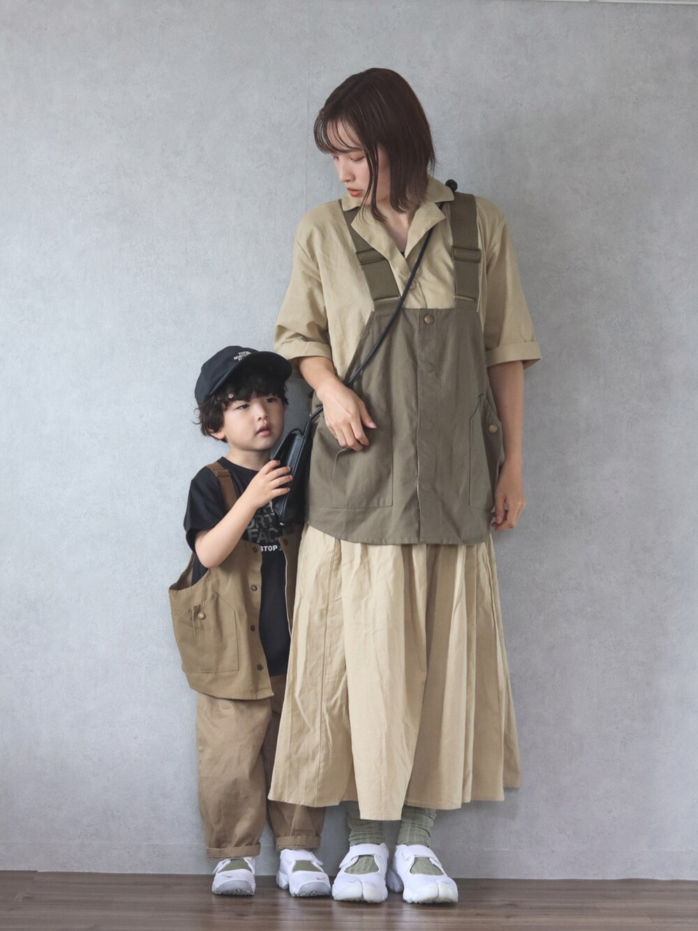 ベージュ系のワンピース、グリーン系のベスト、ホワイト系のスニーカーを着用したキッズの春コーディネートの4枚目の写真