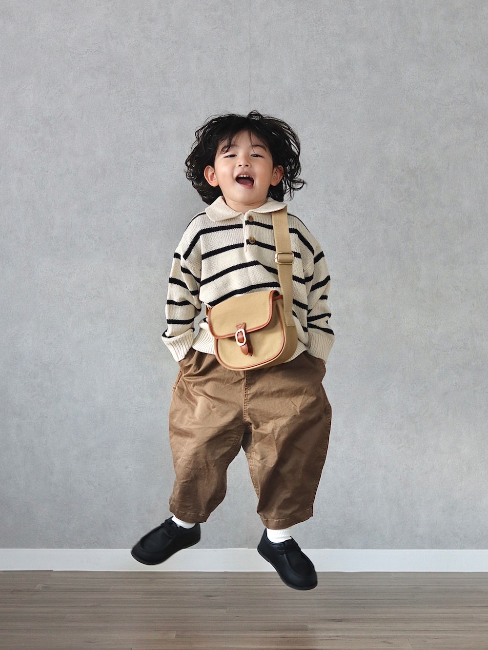ホワイト系のニット/セーター、ブラウン系のチノパンツ、ブラック系のブーツを着用したキッズの秋コーディネートの5枚目の写真