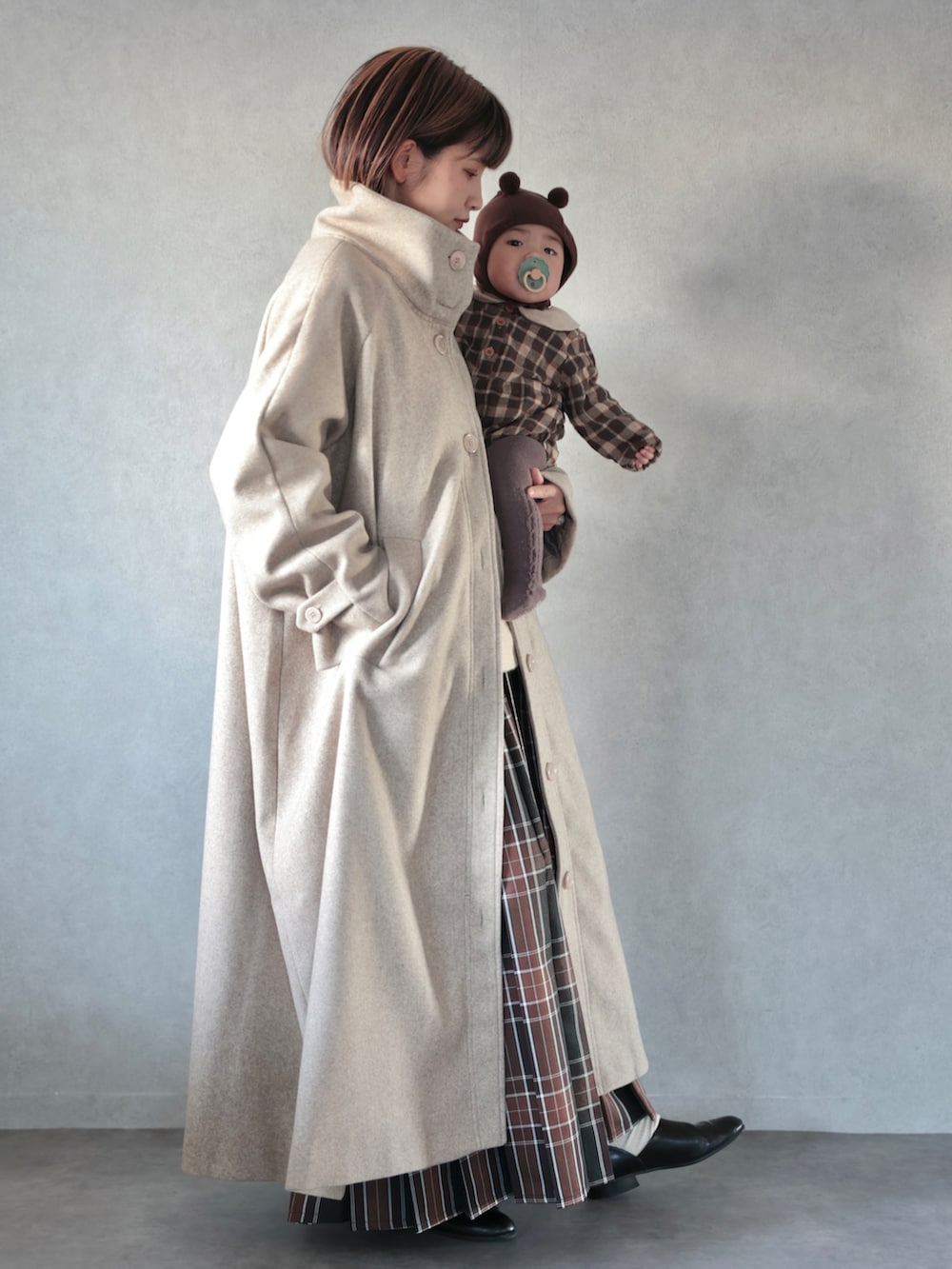 ベージュ系のその他アウター、ホワイト系のニット/セーター、ブラウン系のスカートを着用したキッズの秋コーディネートの2枚目の写真