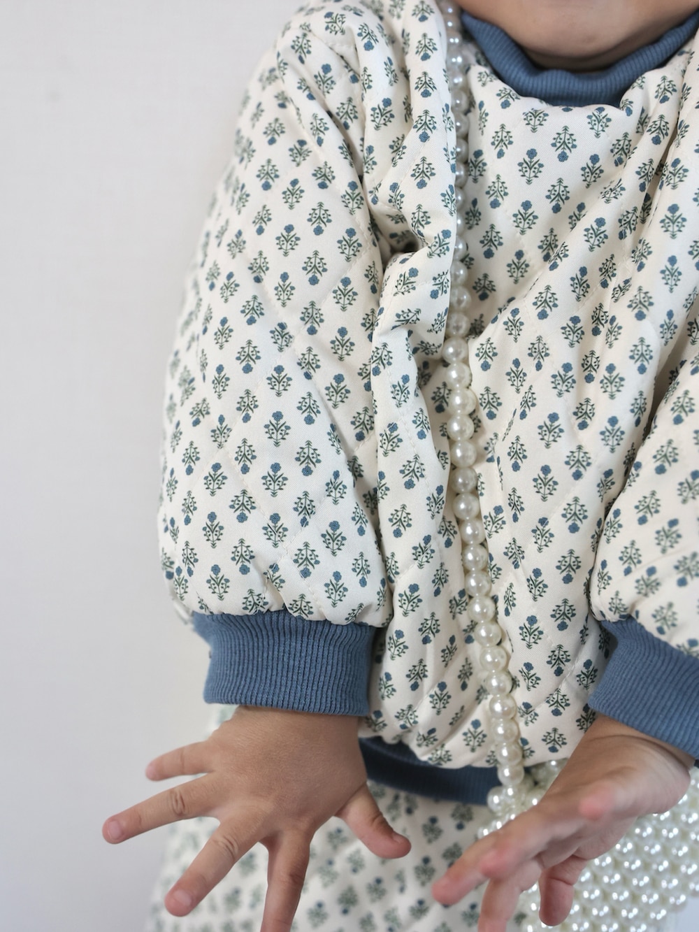 ブラウン系のモカシン/デッキシューズ、ホワイト系のセットアップ、グレー系のその他アウターを着用したキッズの秋コーディネートの4枚目の写真