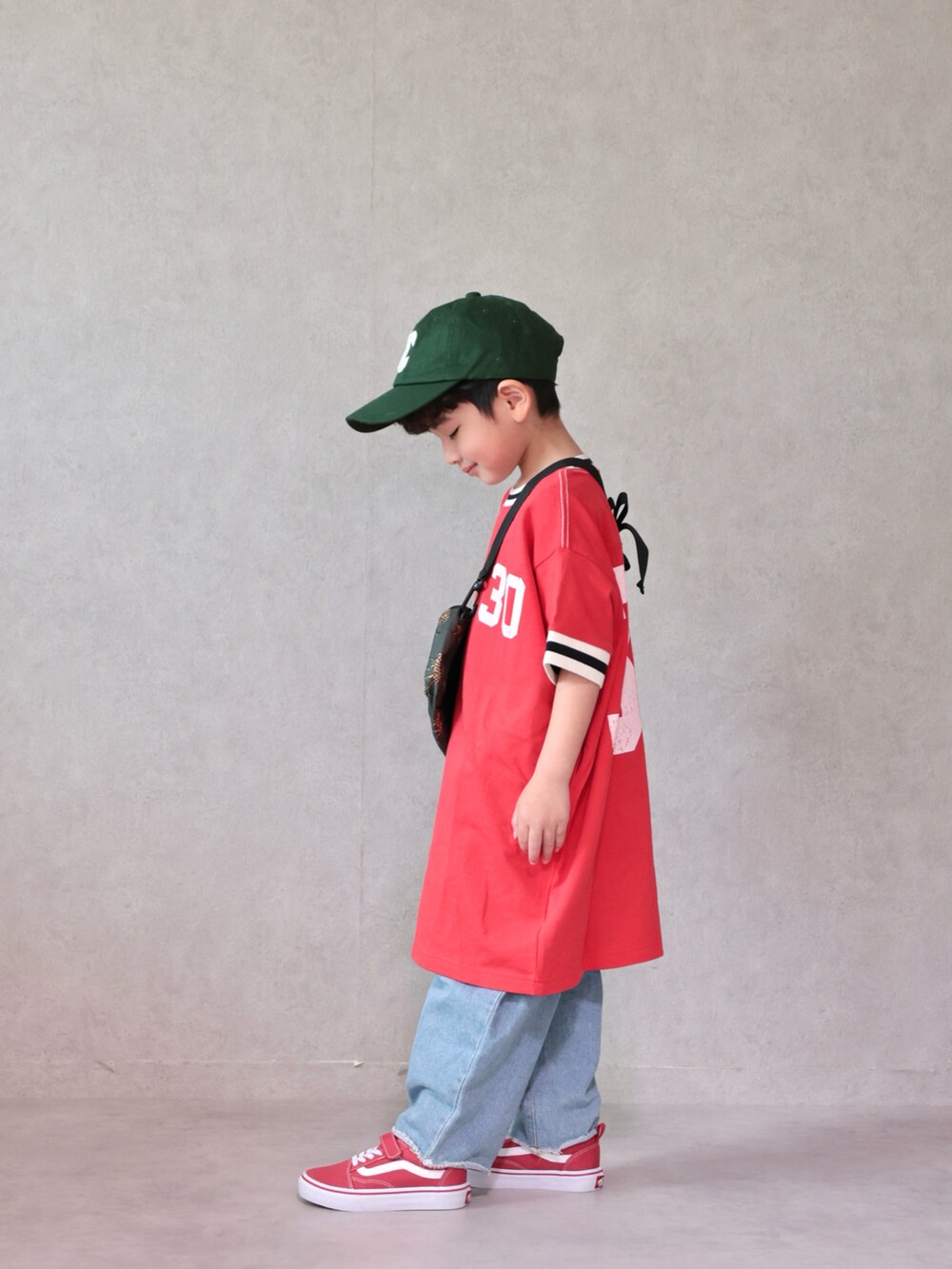レッド系のワンピース、ブルー系のデニムパンツ、レッド系のスニーカーを着用したキッズの春コーディネートの4枚目の写真