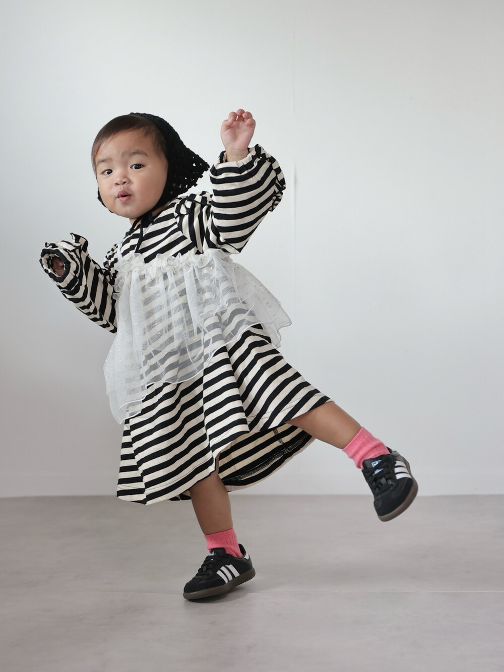 ホワイト系のチュニック、ブラック系のワンピース、ブラック系のスニーカーを着用したキッズの秋コーディネートの4枚目の写真
