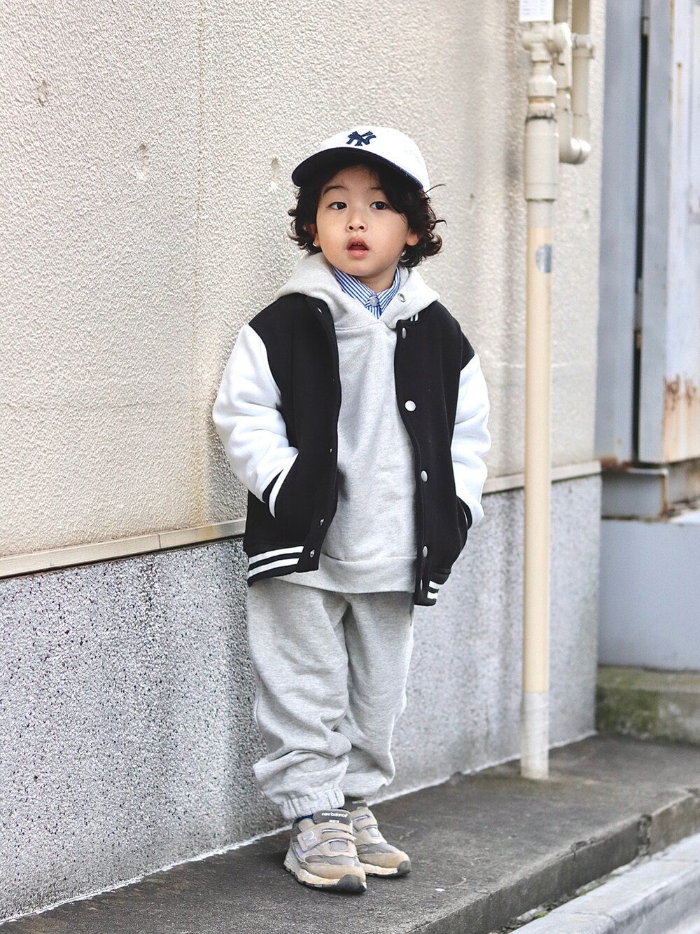 ブラック系のスタジャン、ホワイト系のパーカー、ホワイト系のスウェットパンツを着用したキッズの冬コーディネートの4枚目の写真