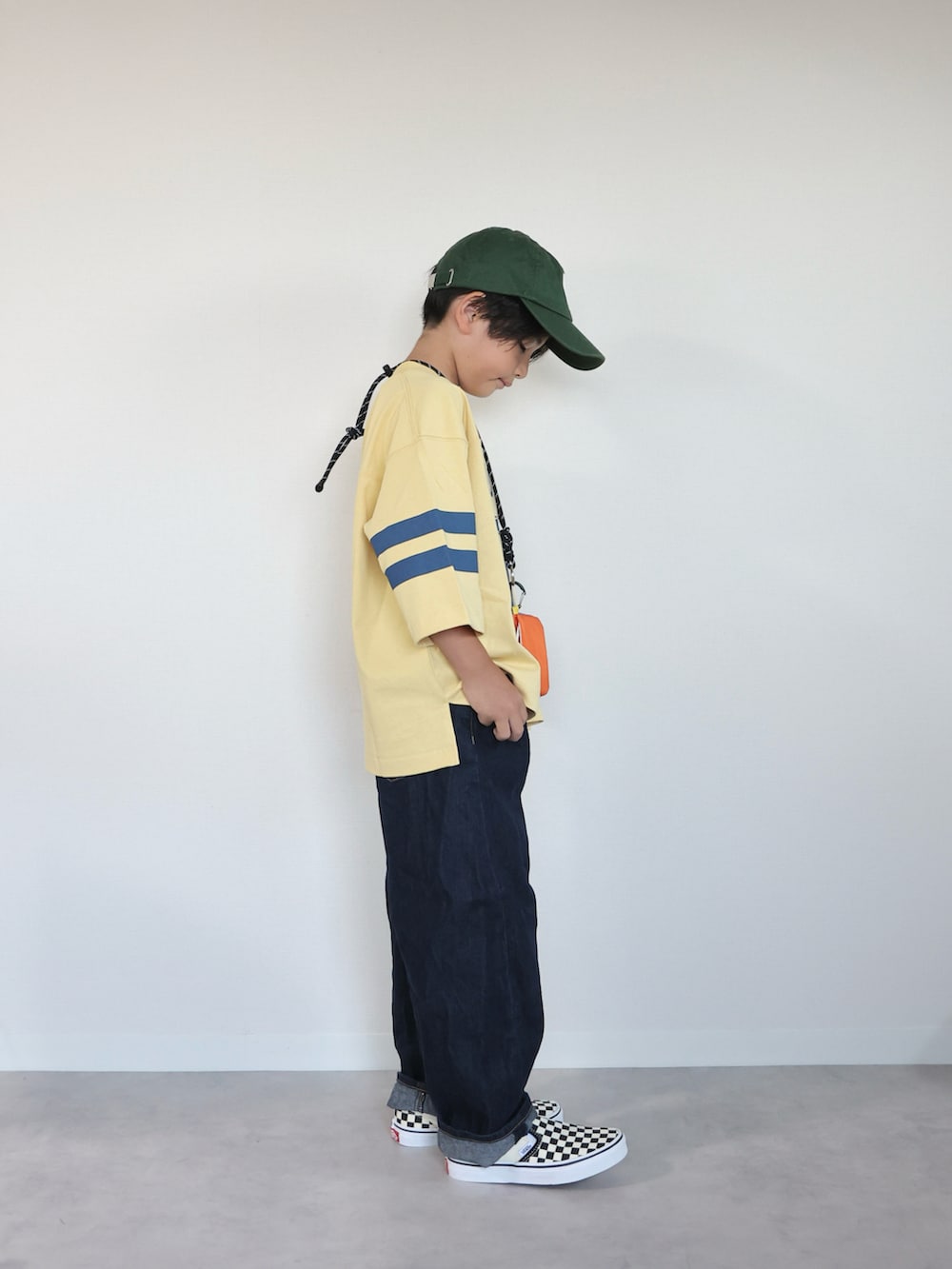 イエロー系のTシャツ/カットソー、ブラック系のスリッポン、ブルー系のパンツを着用したキッズの秋コーディネートの4枚目の写真