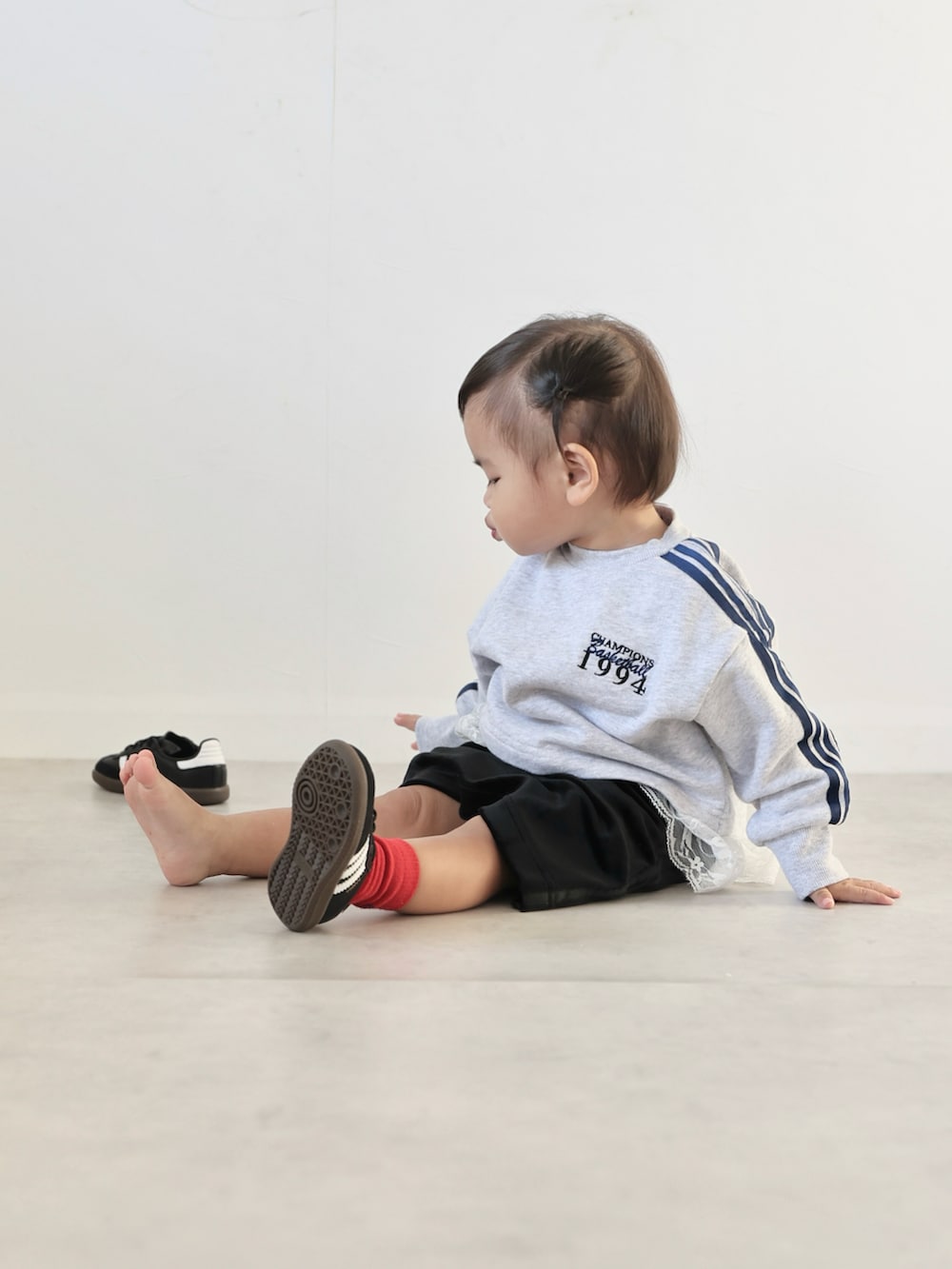 グレー系のスウェット、ブラック系のスカート、ブラック系のスニーカーを着用したキッズの秋コーディネートの4枚目の写真