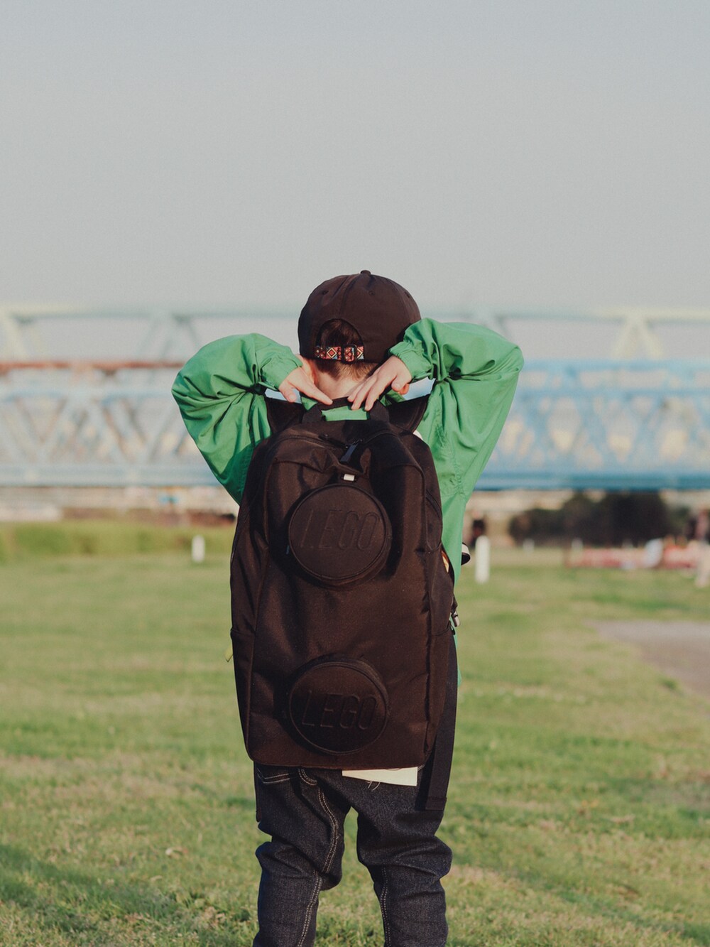 グリーン系のブルゾン、ブルー系のデニムパンツ、グリーン系のスニーカーを着用したキッズの春コーディネートの5枚目の写真