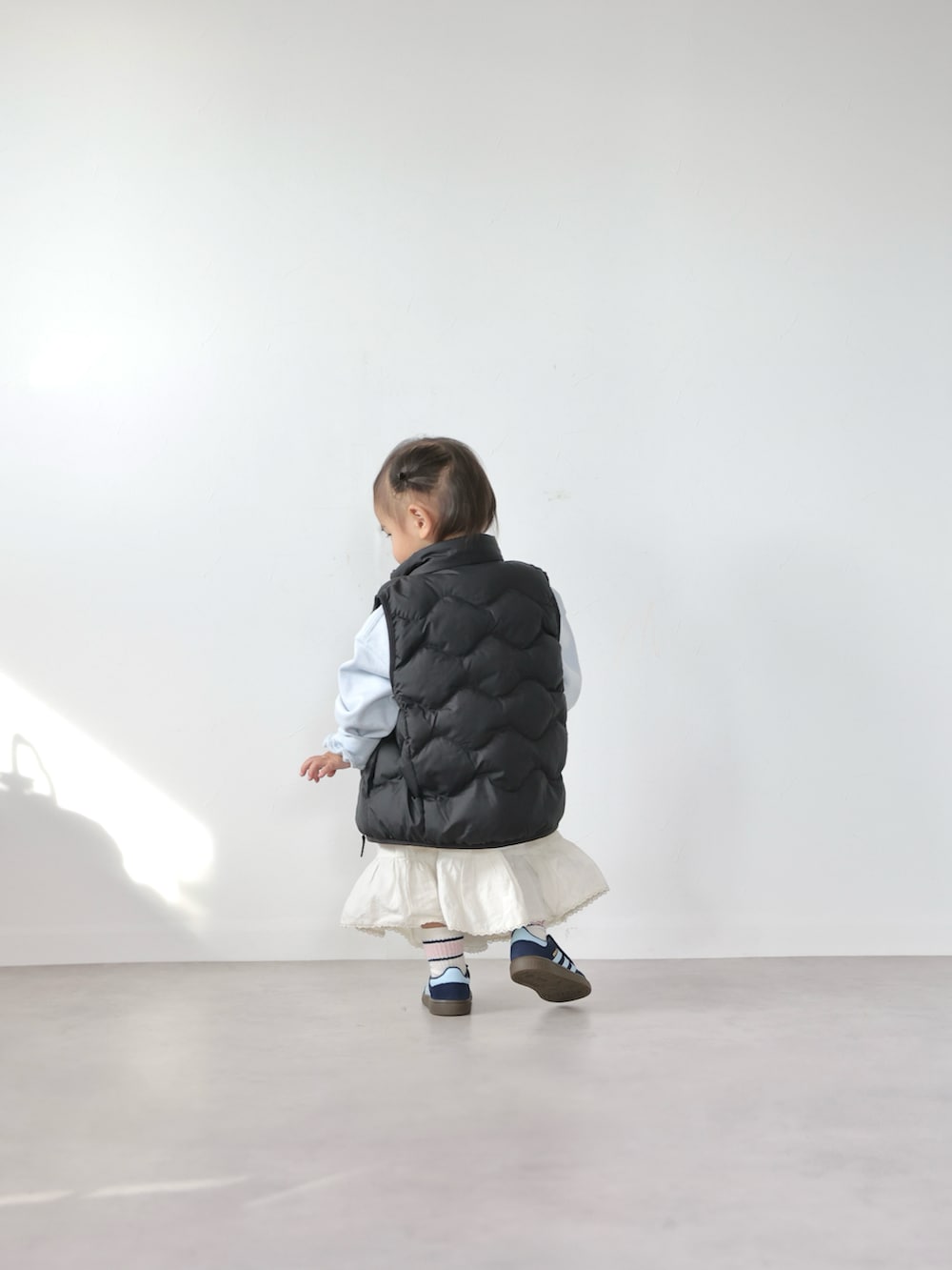 ブルー系のスウェット、ホワイト系のスカート、ブルー系のスニーカーを着用したキッズの冬コーディネートの3枚目の写真