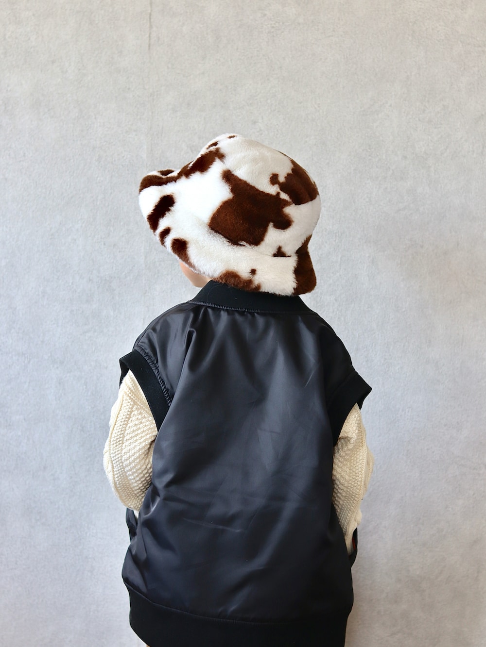 ブラック系のダウンベスト、ホワイト系のニット/セーター、ベージュ系のその他パンツを着用したキッズの秋コーディネートの5枚目の写真