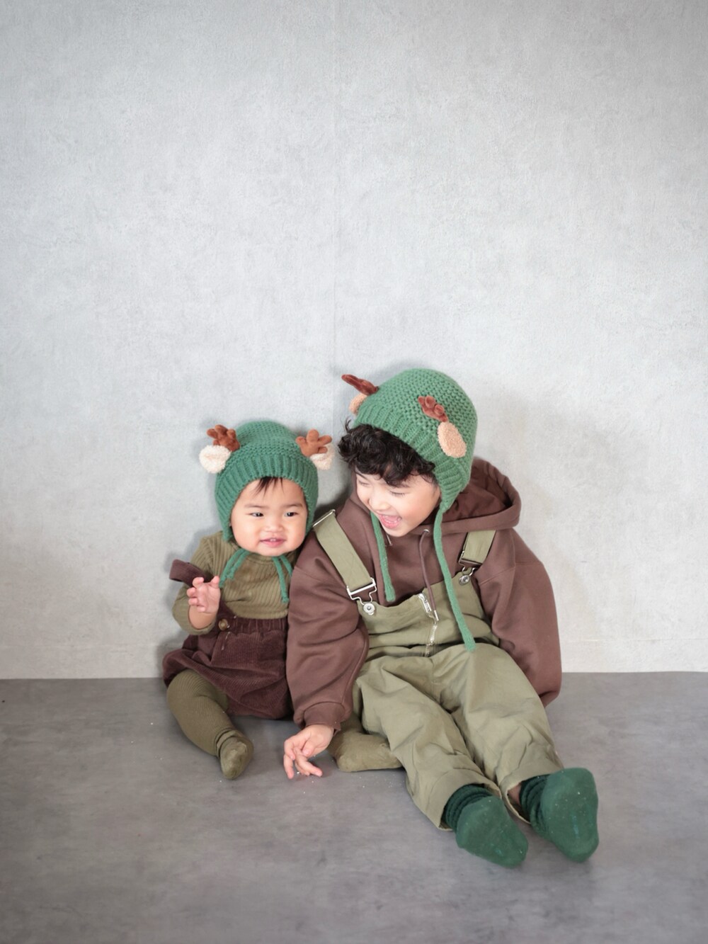 グリーン系のサロペット/オーバーオール、ブラウン系のパーカー、グリーン系のソックス/靴下を着用したキッズの冬コーディネートの2枚目の写真