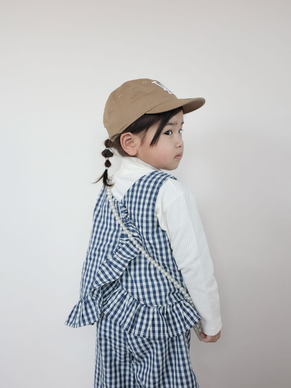 ホワイト系のセットアップ、ブルー系のスニーカー、ホワイト系のショルダーバッグを着用したキッズの春コーディネートの4枚目の写真