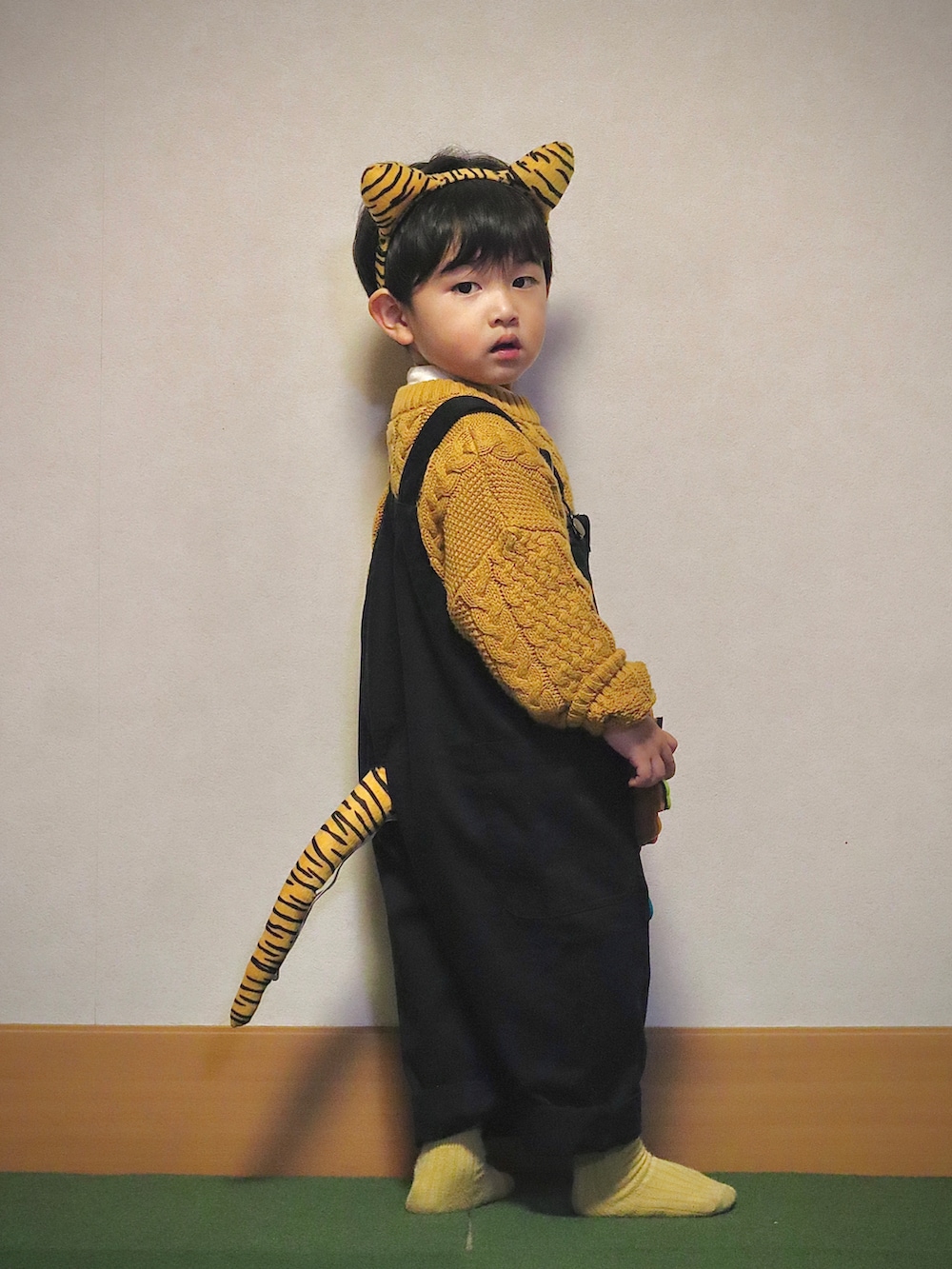 イエロー系のニット/セーター、ホワイト系のシャツ/ブラウス、ブラック系のデニムパンツを着用したキッズの冬コーディネートの2枚目の写真
