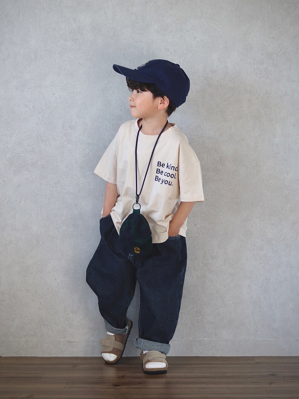 ベージュ系のトップス、ブルー系のデニムパンツ、ベージュ系のサンダルを着用したキッズの春コーディネートの4枚目の写真
