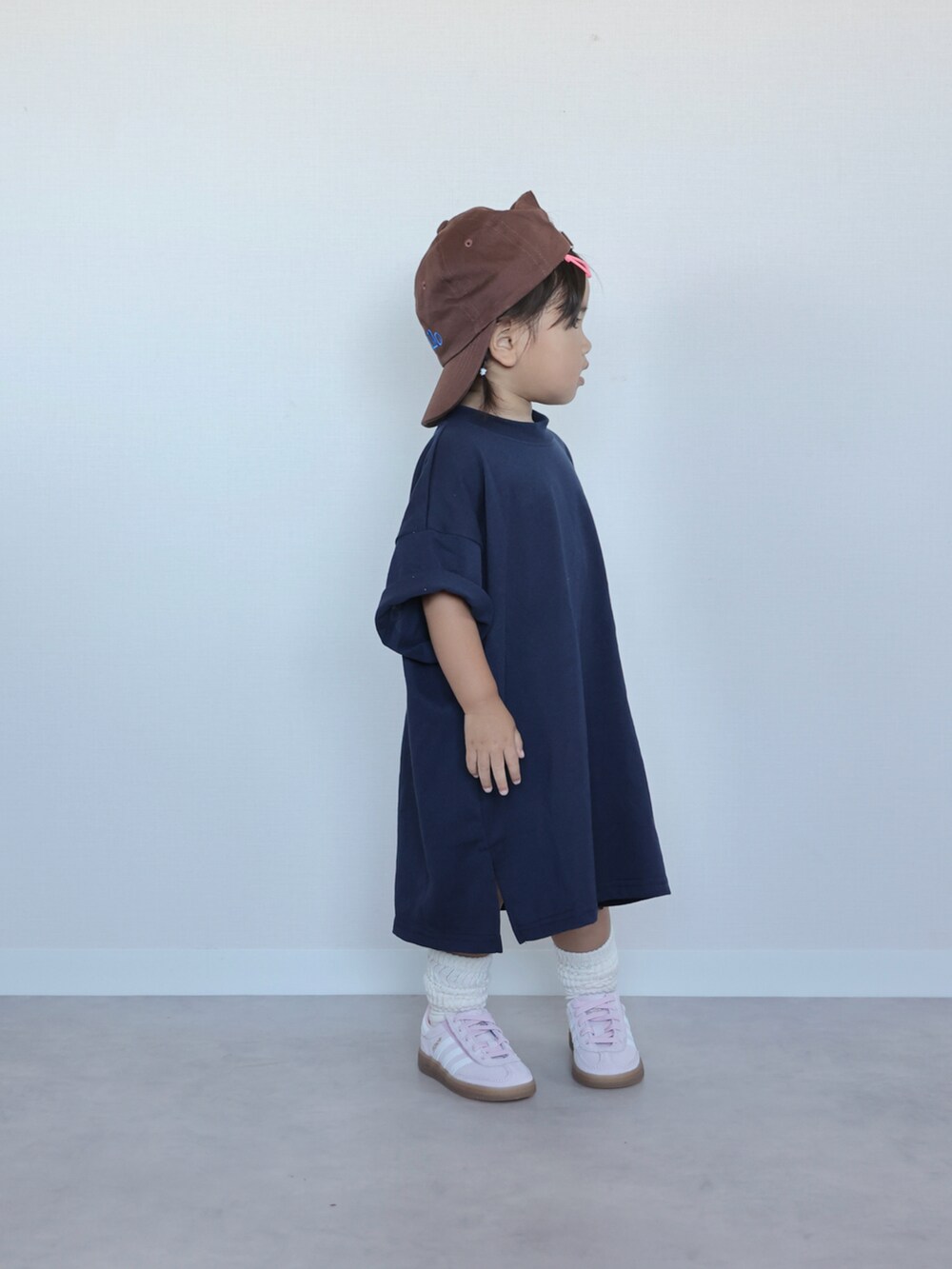 ブルー系のワンピース、ピンク系のスニーカー、ブラウン系のキャップを着用したキッズの夏コーディネートの2枚目の写真