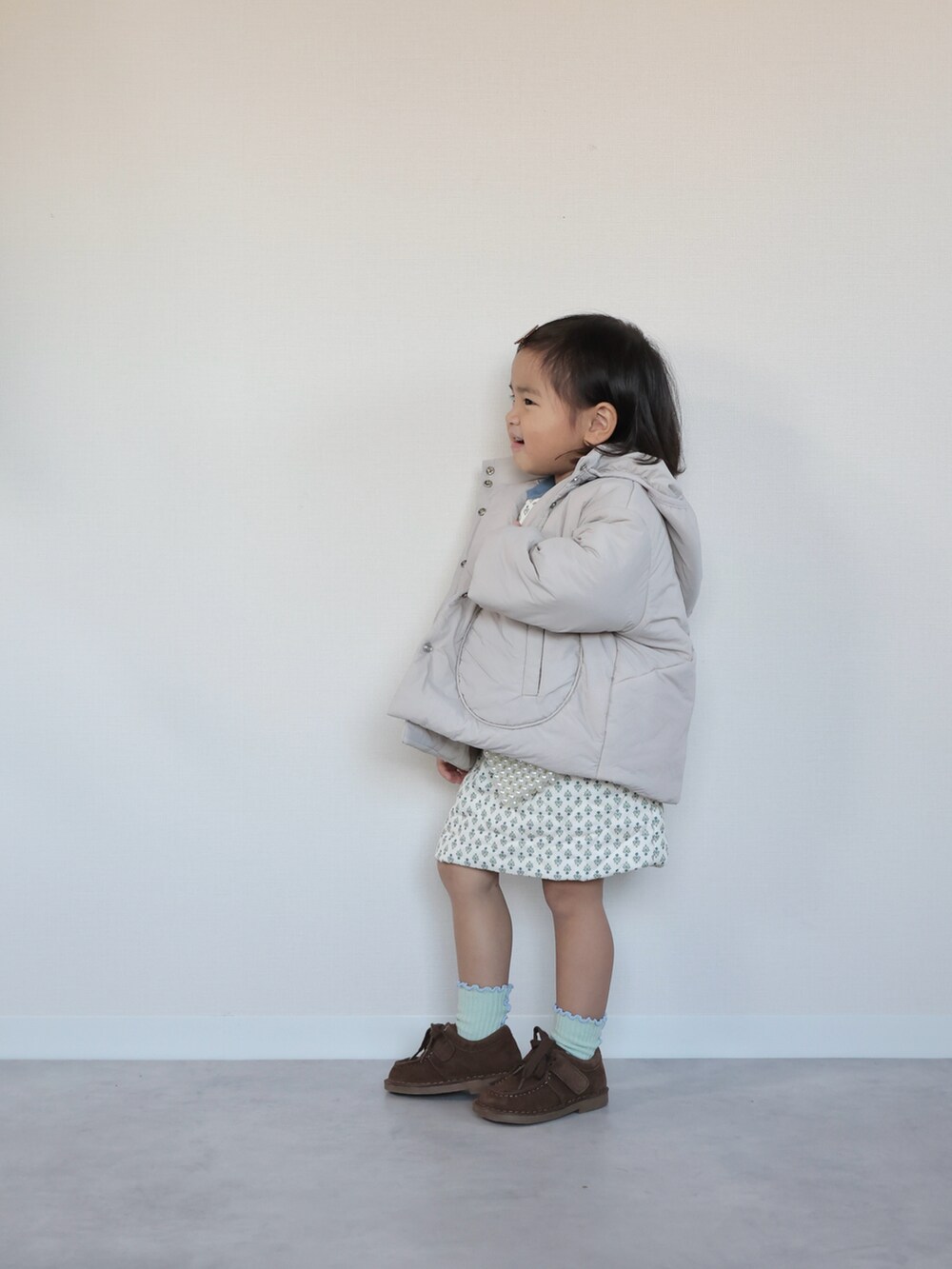 ブラウン系のモカシン/デッキシューズ、ホワイト系のセットアップ、グレー系のその他アウターを着用したキッズの秋コーディネートの2枚目の写真