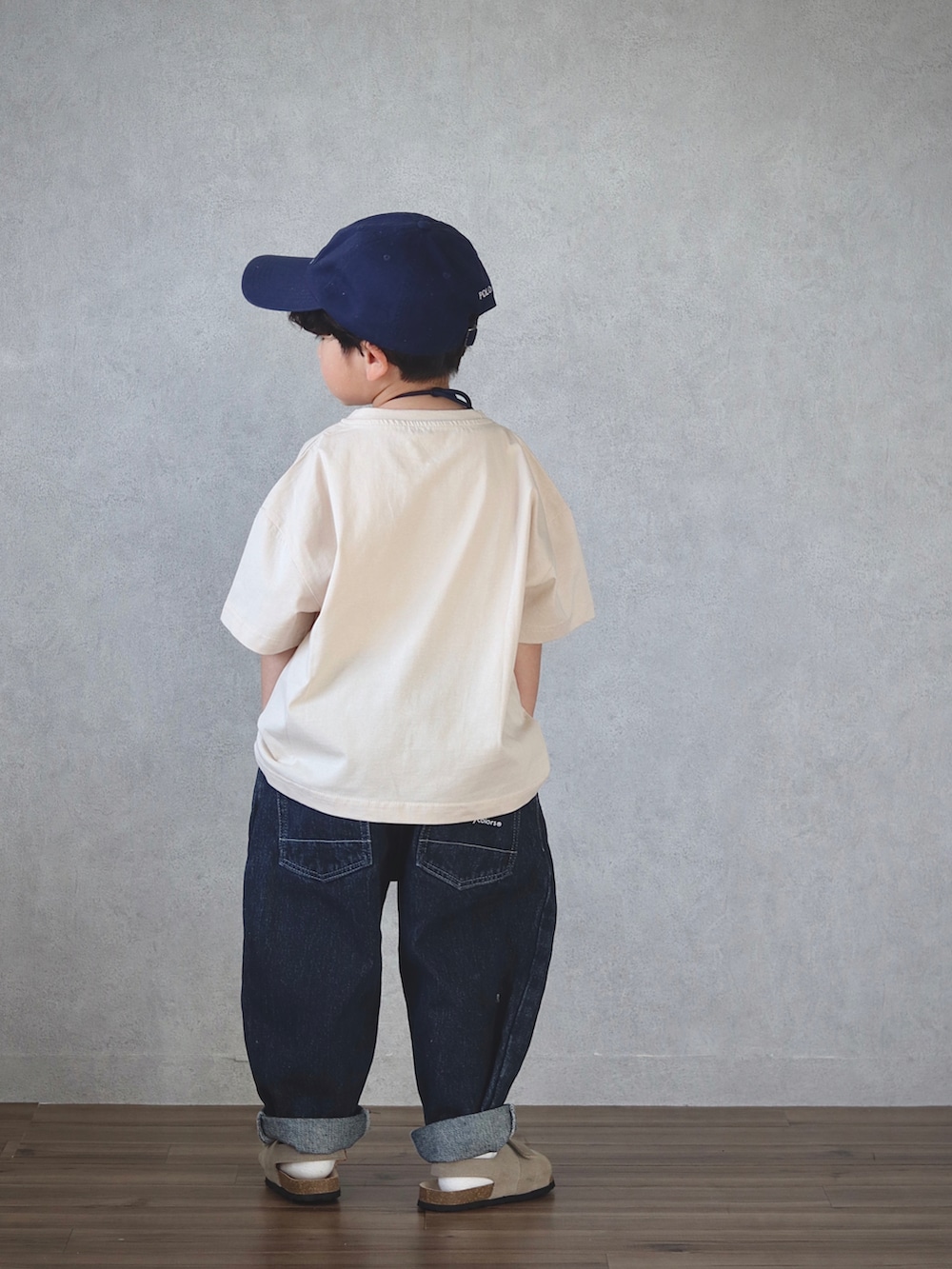 ベージュ系のトップス、ブルー系のデニムパンツ、ベージュ系のサンダルを着用したキッズの春コーディネートの3枚目の写真