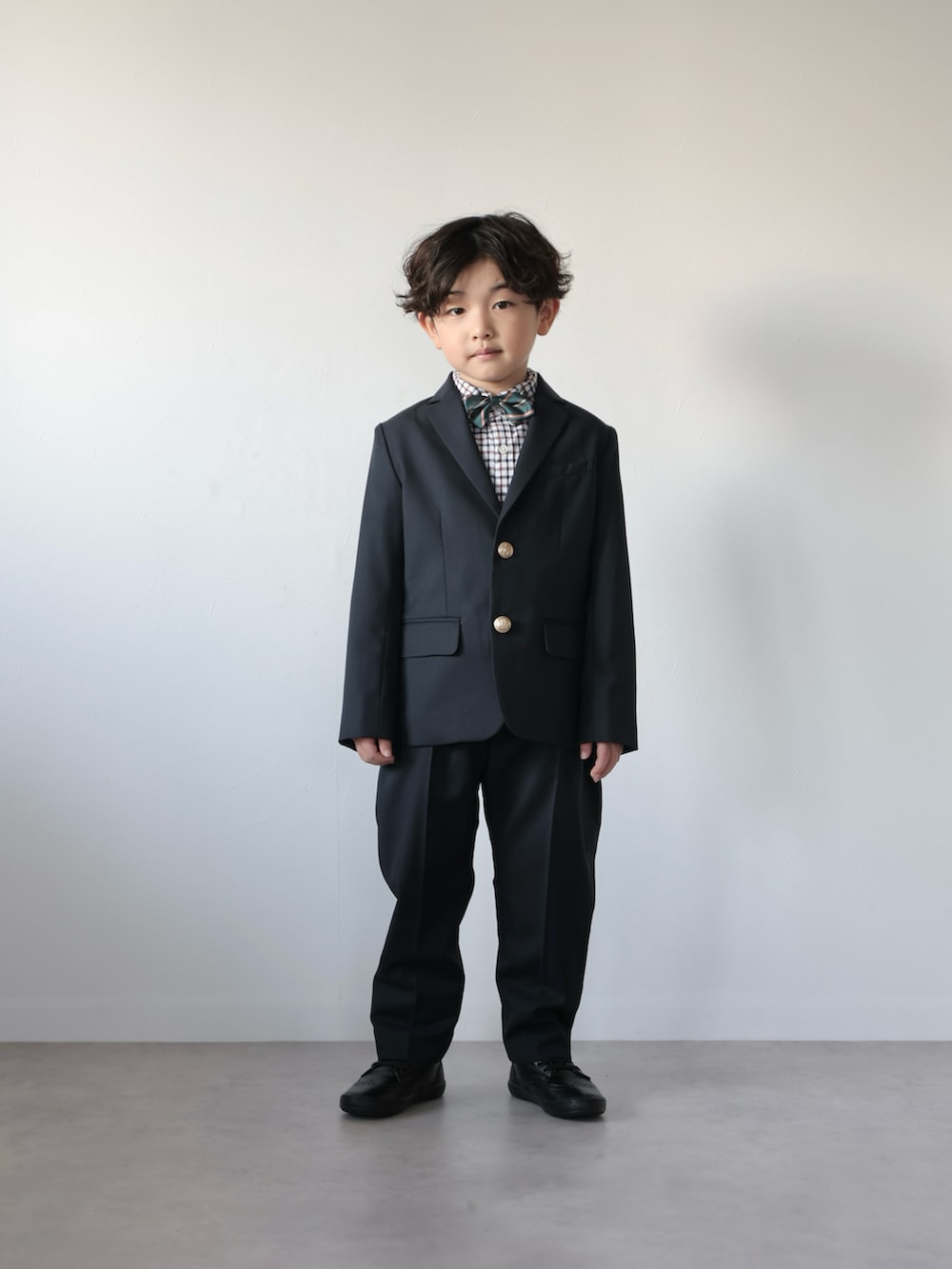 ブルー系のスーツジャケット、ブルー系のスーツパンツ、グリーン系の蝶ネクタイを着用したキッズの冬コーディネートの5枚目の写真