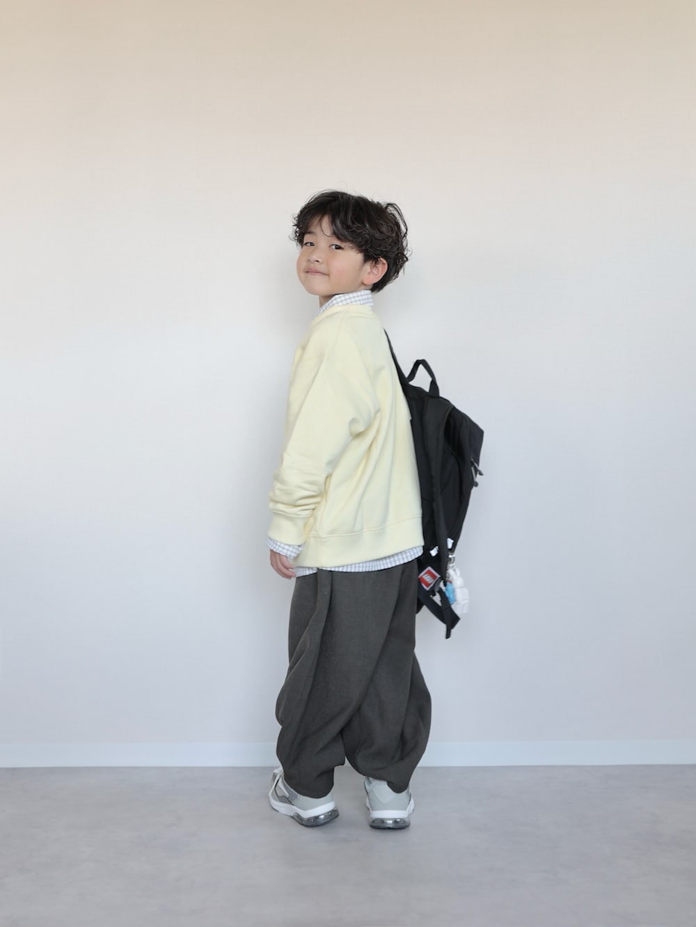 イエロー系のトップス、ホワイト系のシャツ/ブラウス、グレー系のその他パンツを着用したキッズの春コーディネートの2枚目の写真