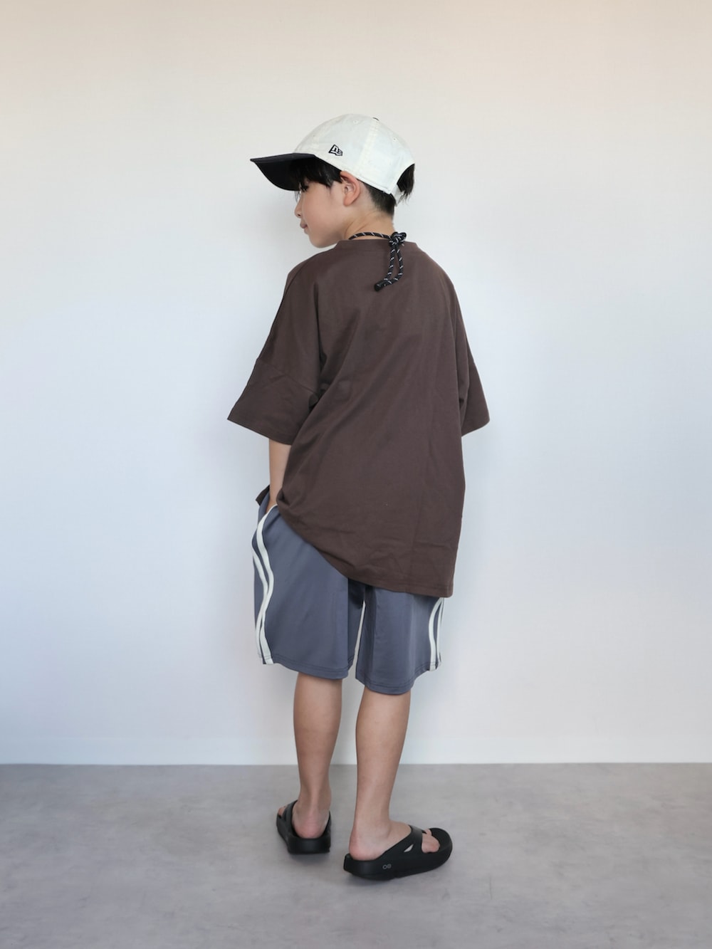 ブラウン系のTシャツ/カットソー、ブラック系のサンダル、グレー系のスウェットパンツを着用したキッズの夏コーディネートの3枚目の写真