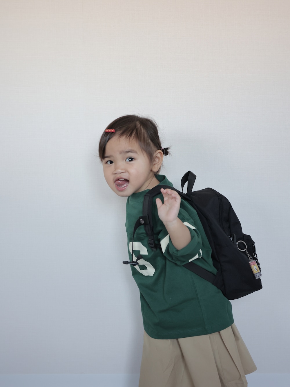 グリーン系のTシャツ/カットソー、ベージュ系のジャンパースカート、ブラック系のスニーカーを着用したキッズの春コーディネートの4枚目の写真