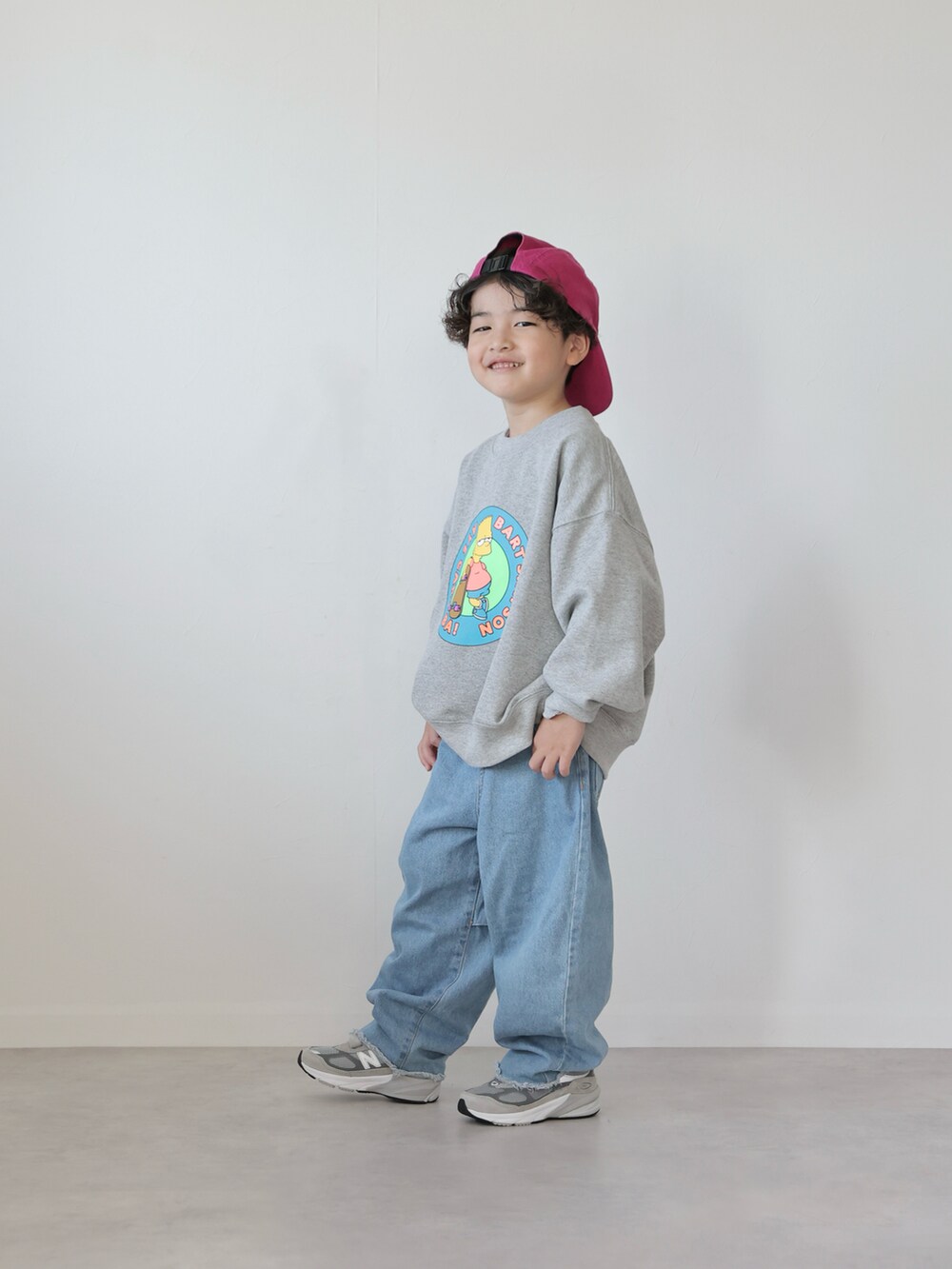 グレー系のスウェット、ブラック系のトップス、ブルー系のデニムパンツを着用したキッズの冬コーディネートの2枚目の写真