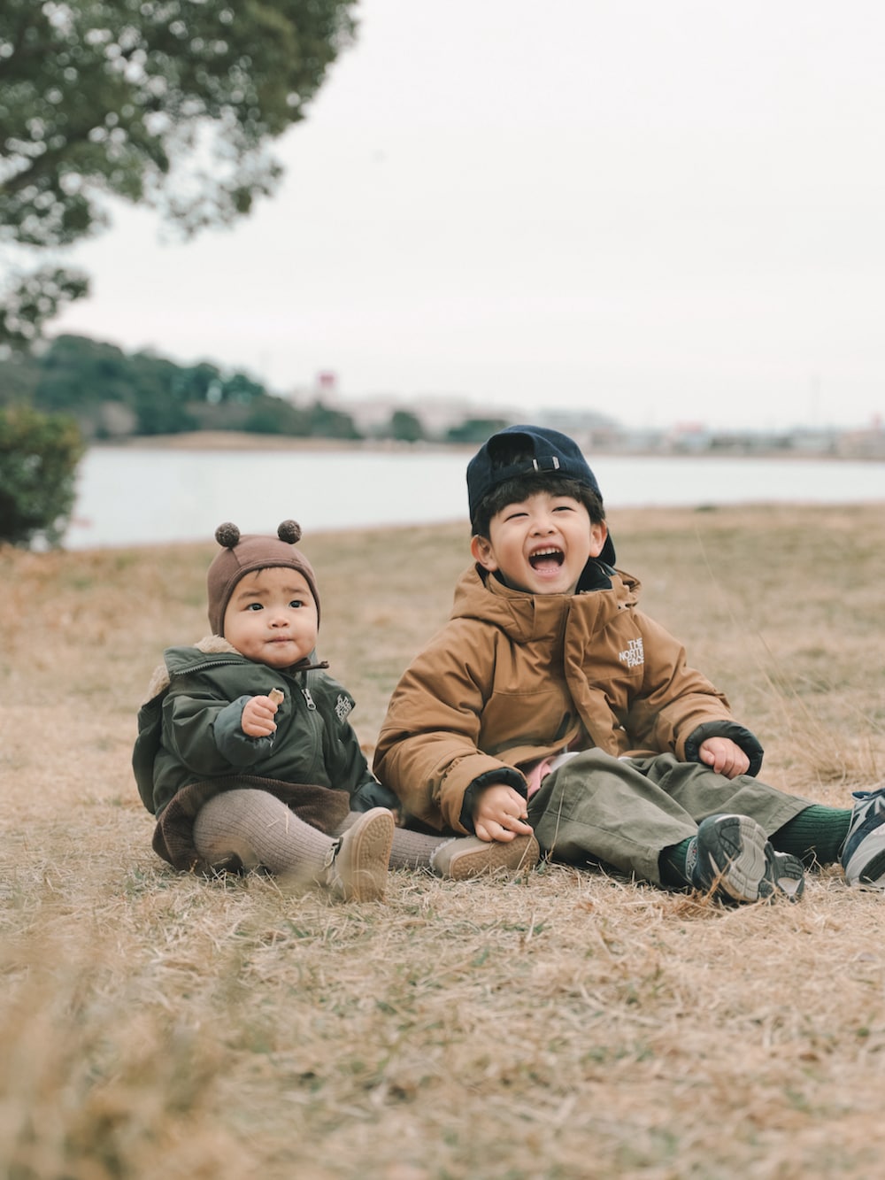 ブラウン系のその他アウター、グリーン系のカーゴパンツ、ブルー系のスニーカーを着用したキッズの冬コーディネートの2枚目の写真