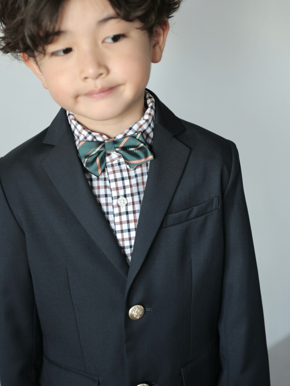 ブルー系のスーツジャケット、ブルー系のスーツパンツ、グリーン系の蝶ネクタイを着用したキッズの冬コーディネートの3枚目の写真