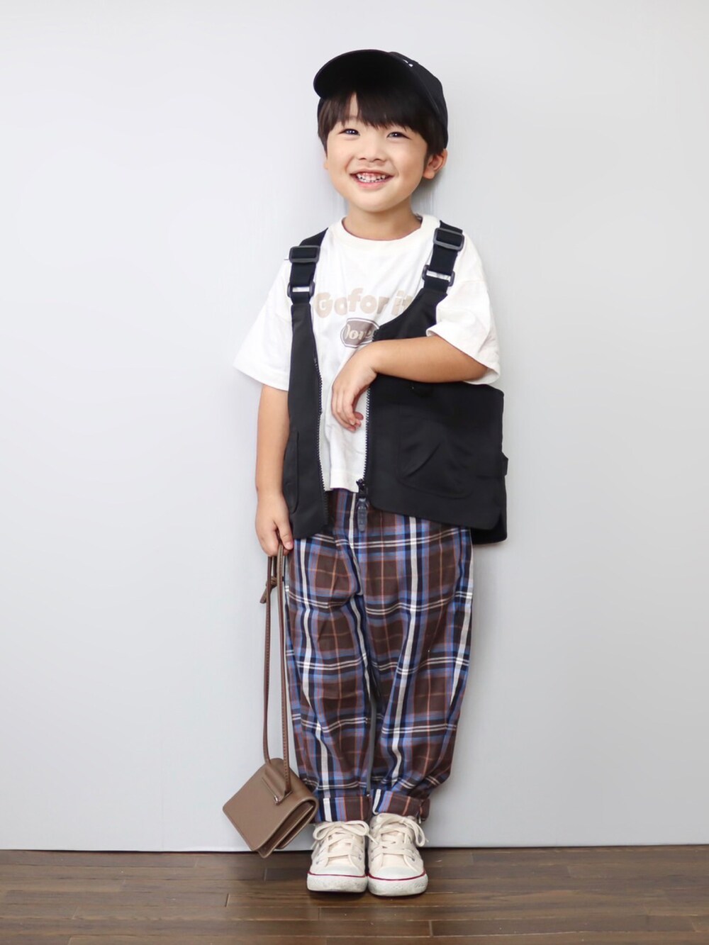 ホワイト系のTシャツ/カットソー、ブラック系のベスト、ブラウン系のパンツを着用したキッズの秋コーディネートの3枚目の写真