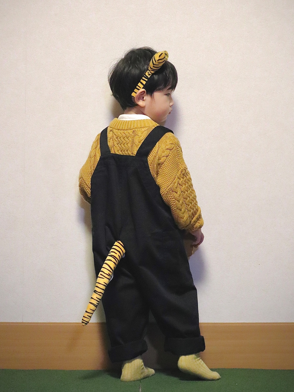 イエロー系のニット/セーター、ホワイト系のシャツ/ブラウス、ブラック系のデニムパンツを着用したキッズの冬コーディネートの4枚目の写真