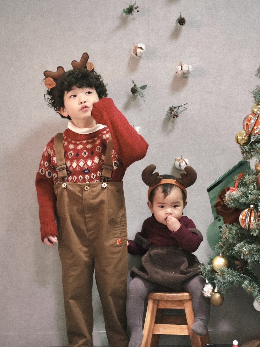 レッド系のニット/セーター、ホワイト系のTシャツ/カットソー、ブラウン系のサロペット/オーバーオールを着用したキッズの冬コーディネートの2枚目の写真