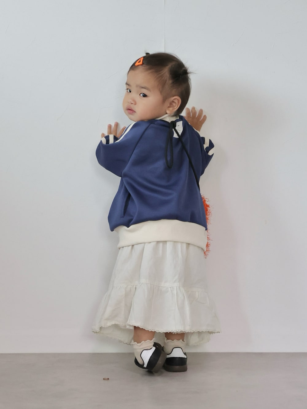 オレンジ系のショルダーバッグ、ブルー系のジャケット/アウター、ホワイト系のスカートを着用したキッズの秋コーディネートの4枚目の写真