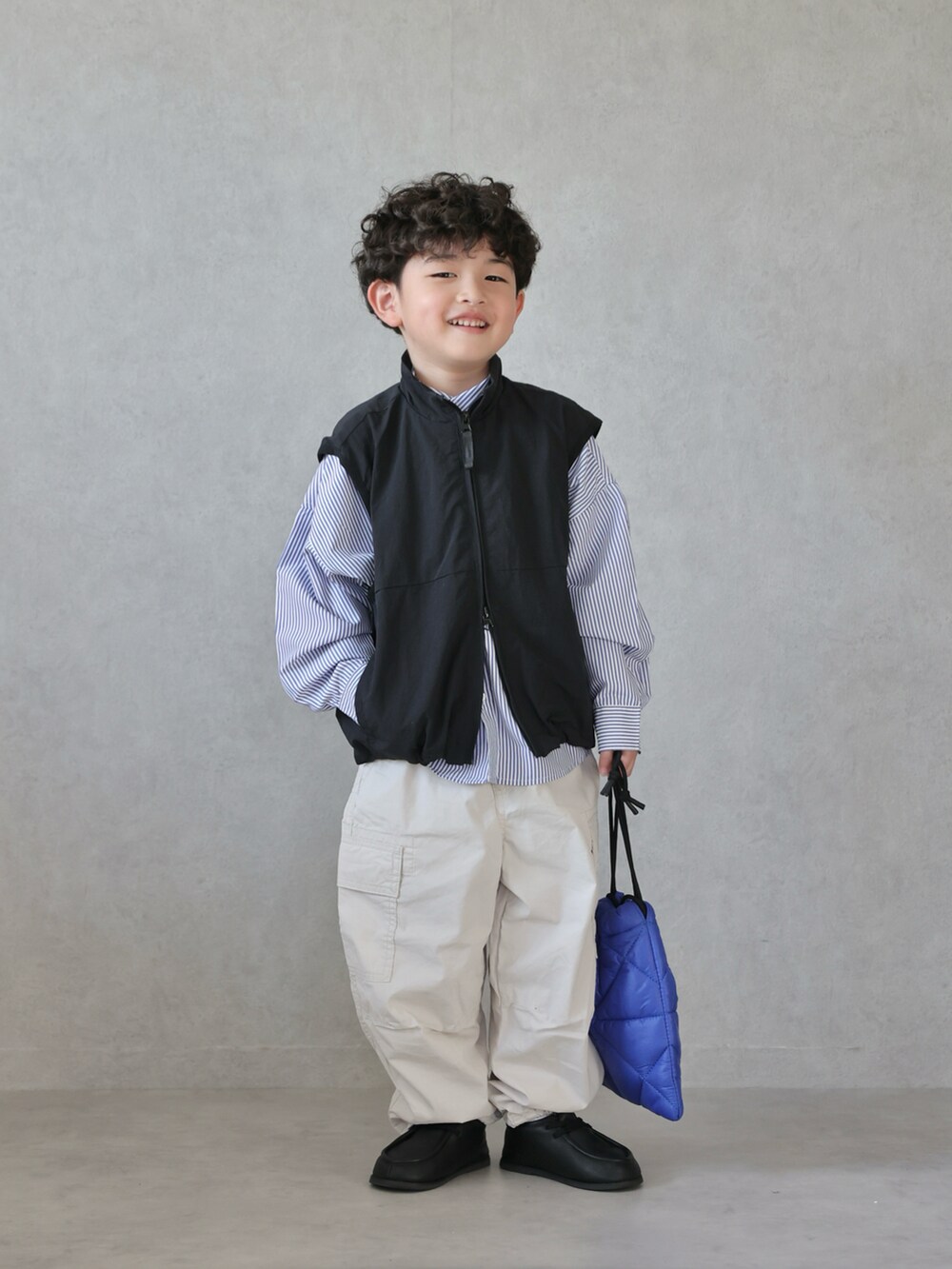 ブラック系のベスト、ブルー系のシャツ/ブラウス、ホワイト系のパンツを着用したキッズの春コーディネートの2枚目の写真