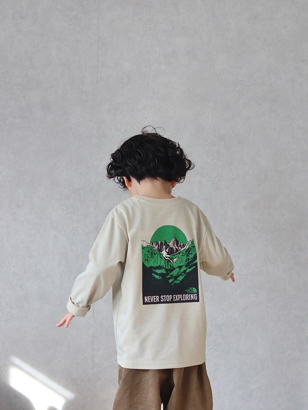 グリーン系のブルゾン、ベージュ系のTシャツ/カットソー、ブラウン系のチノパンツを着用したキッズの冬コーディネートの4枚目の写真