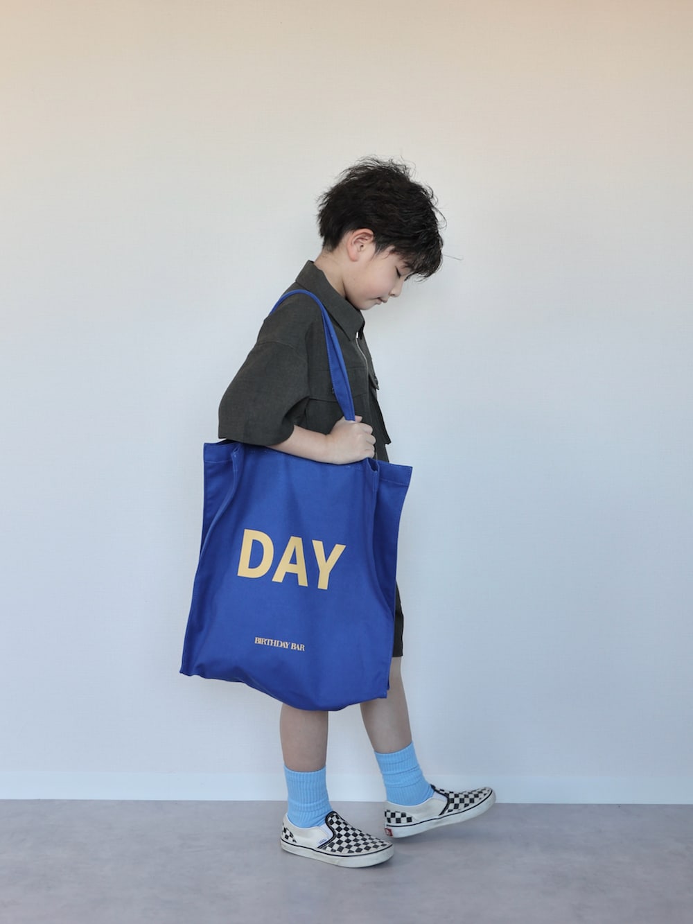 グレー系のつなぎ/オールインワン、ブルー系のトートバッグ、ブラック系のスリッポンを着用したキッズの春コーディネートの2枚目の写真