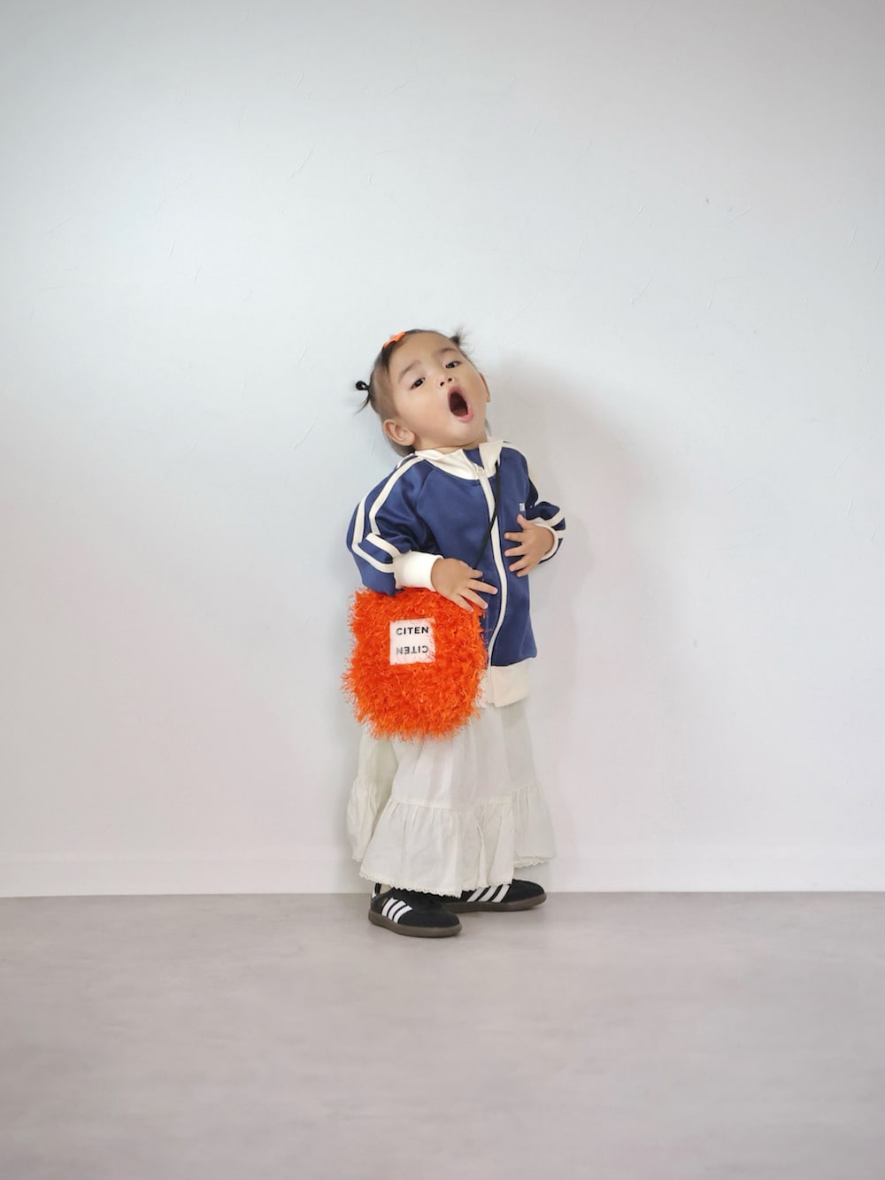 オレンジ系のショルダーバッグ、ブルー系のジャケット/アウター、ホワイト系のスカートを着用したキッズの秋コーディネートの5枚目の写真