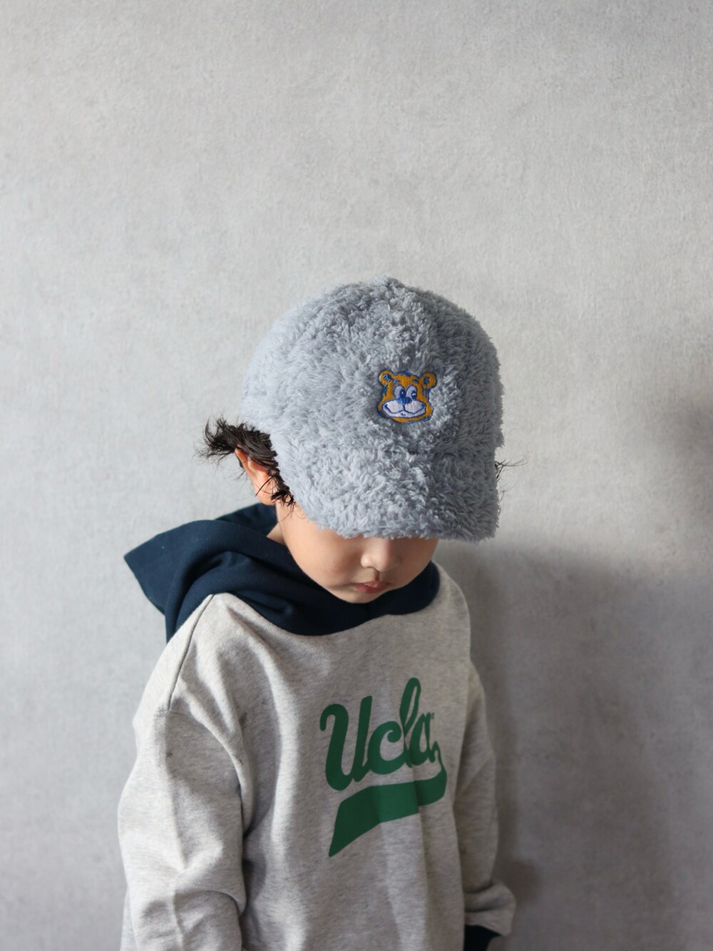 ホワイト系のパーカー、ブルー系のデニムパンツ、グリーン系のスニーカーを着用したキッズの秋コーディネートの4枚目の写真