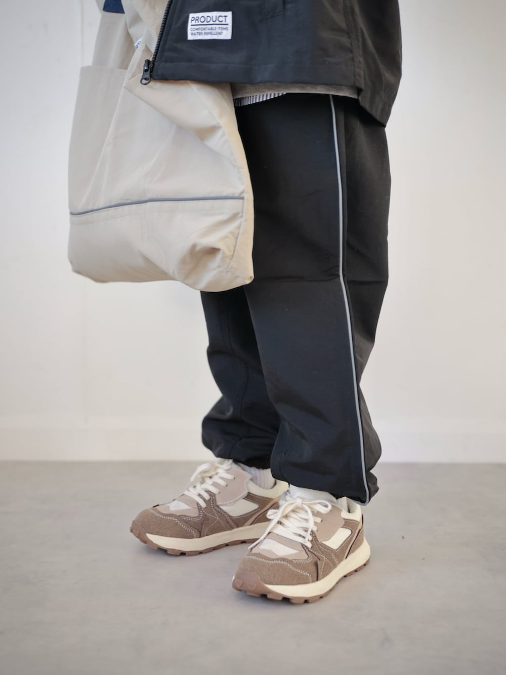 ブラック系のマウンテンパーカー、ブラック系のその他パンツ、グレー系のスウェットを着用したキッズの冬コーディネートの4枚目の写真