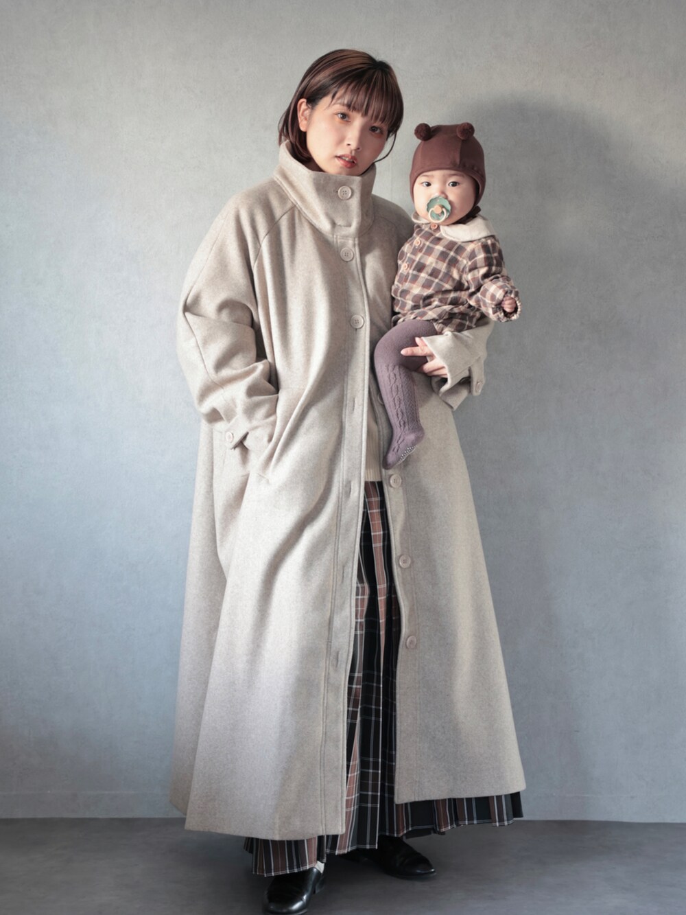 ベージュ系のその他アウター、ホワイト系のニット/セーター、ブラウン系のスカートを着用したキッズの秋コーディネートの5枚目の写真