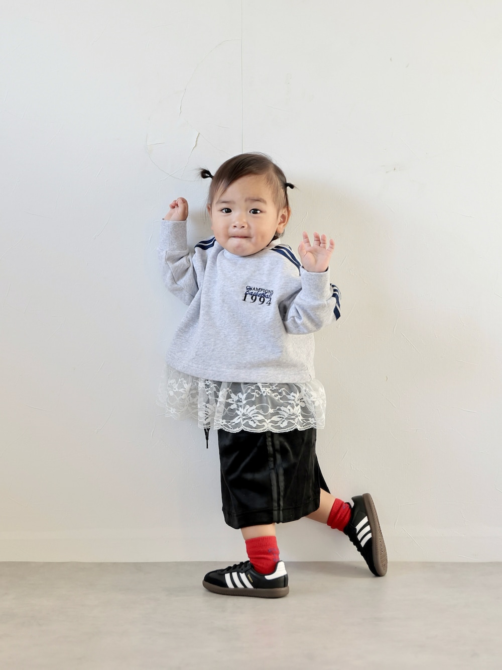 グレー系のスウェット、ブラック系のスカート、ブラック系のスニーカーを着用したキッズの秋コーディネートの2枚目の写真