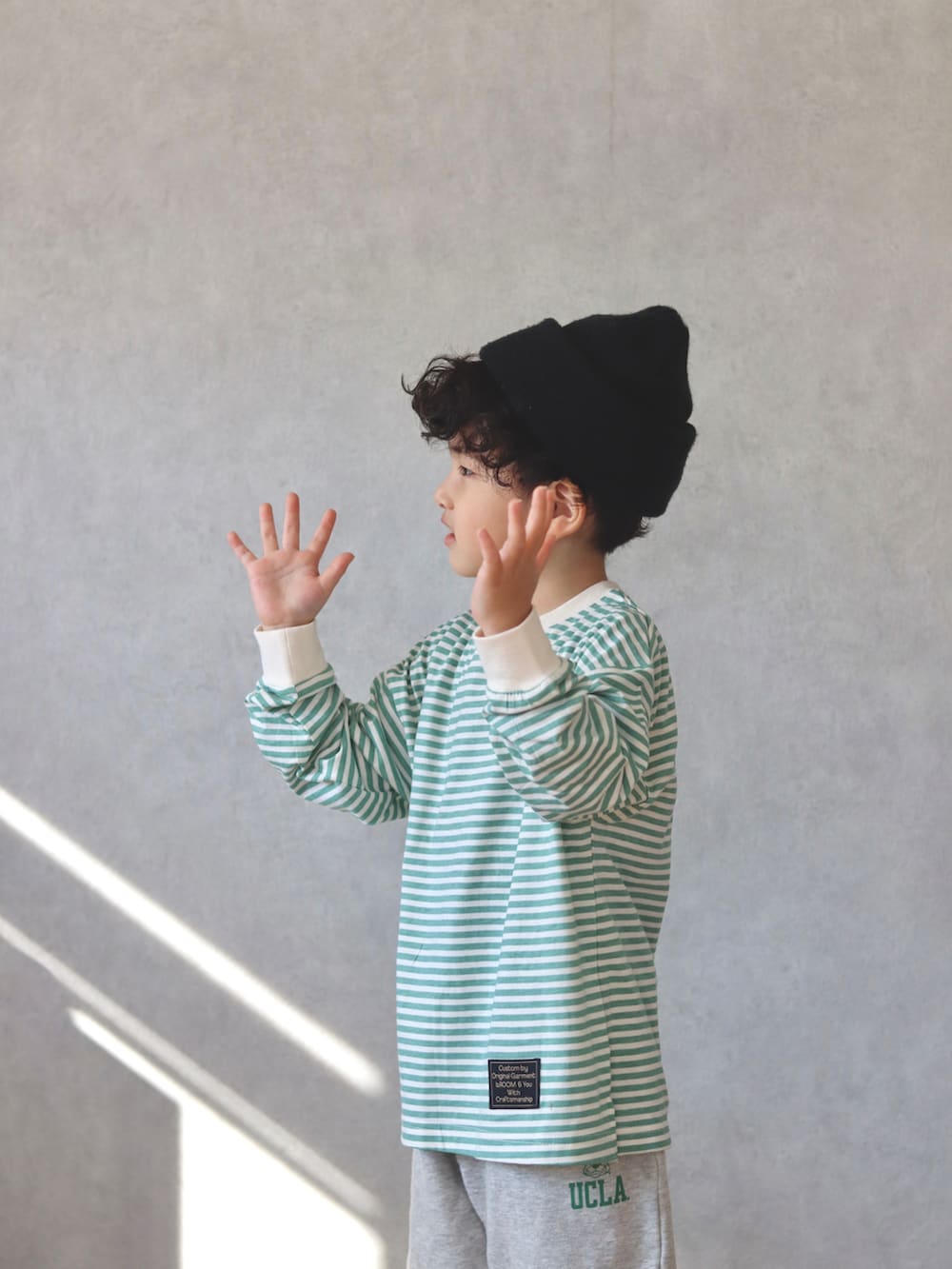 グリーン系のTシャツ/カットソー、ホワイト系のスウェットパンツ、ベージュ系のショルダーバッグを着用したキッズの冬コーディネートの3枚目の写真