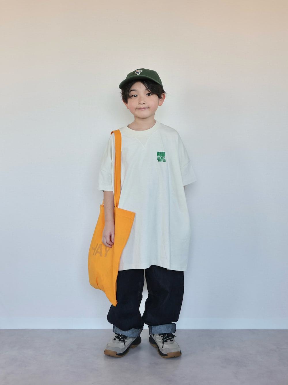 ホワイト系のTシャツ/カットソー、オレンジ系のトートバッグ、ベージュ系のスニーカーを着用したキッズの春コーディネートの4枚目の写真