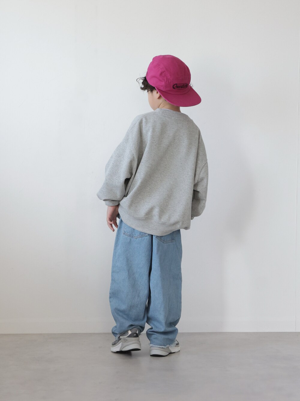 グレー系のスウェット、ブラック系のトップス、ブルー系のデニムパンツを着用したキッズの冬コーディネートの3枚目の写真