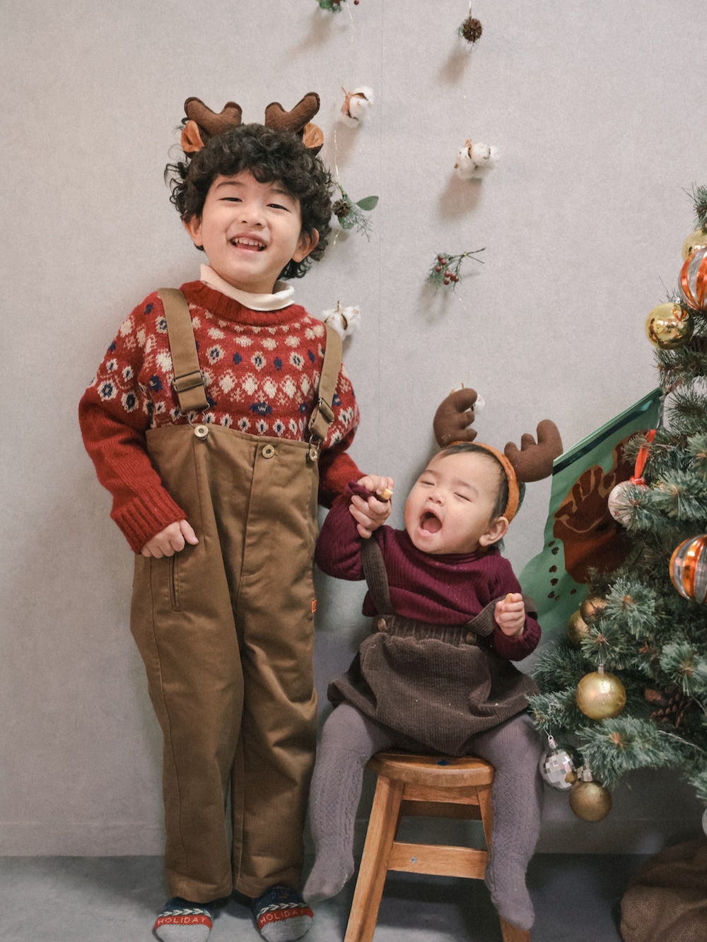 レッド系のニット/セーター、ホワイト系のTシャツ/カットソー、ブラウン系のサロペット/オーバーオールを着用したキッズの冬コーディネートの3枚目の写真