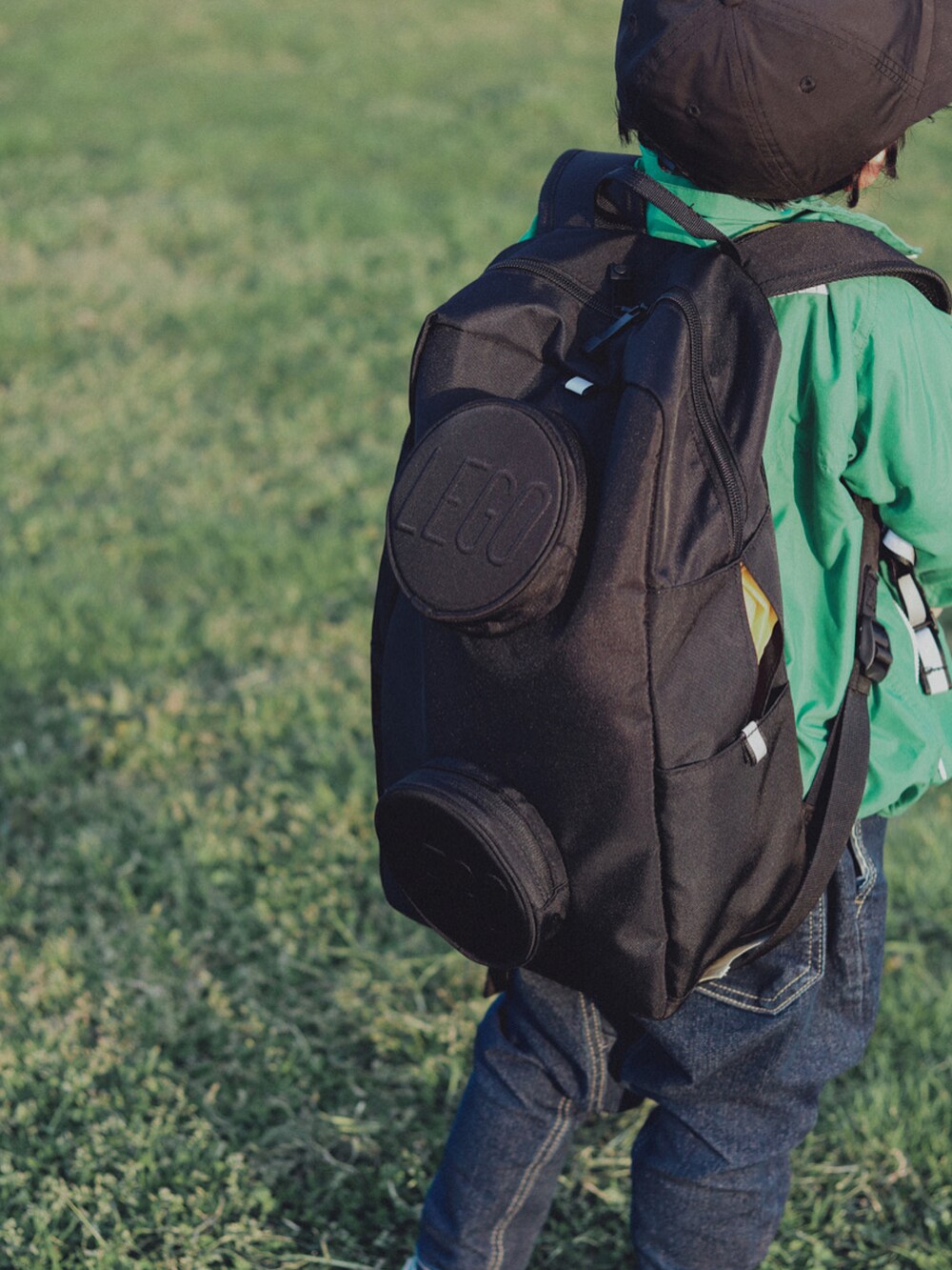 グリーン系のブルゾン、ブルー系のデニムパンツ、グリーン系のスニーカーを着用したキッズの春コーディネートの3枚目の写真