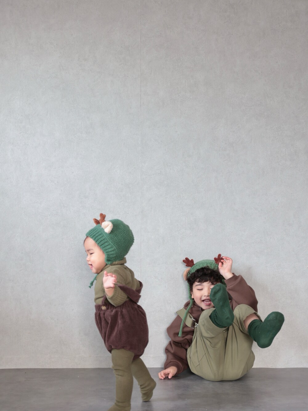 グリーン系のサロペット/オーバーオール、ブラウン系のパーカー、グリーン系のソックス/靴下を着用したキッズの冬コーディネートの5枚目の写真