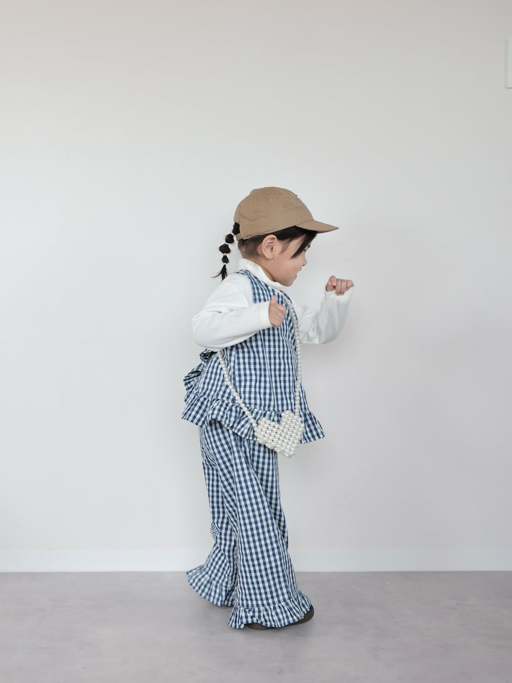 ホワイト系のセットアップ、ブルー系のスニーカー、ホワイト系のショルダーバッグを着用したキッズの春コーディネートの2枚目の写真