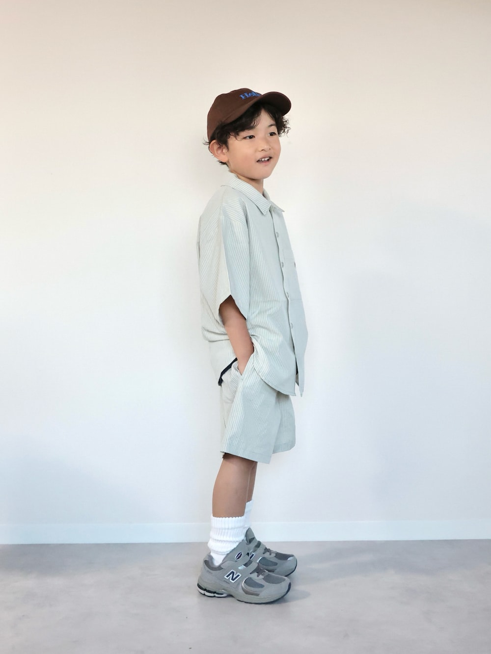 グリーン系のセットアップ、グレー系のスニーカー、ブラウン系のキャップを着用したキッズの夏コーディネートの5枚目の写真