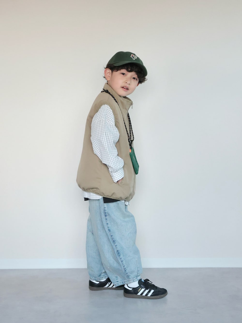 ベージュ系のベスト、ホワイト系のシャツ/ブラウス、ブルー系のデニムパンツを着用したキッズの春コーディネートの2枚目の写真